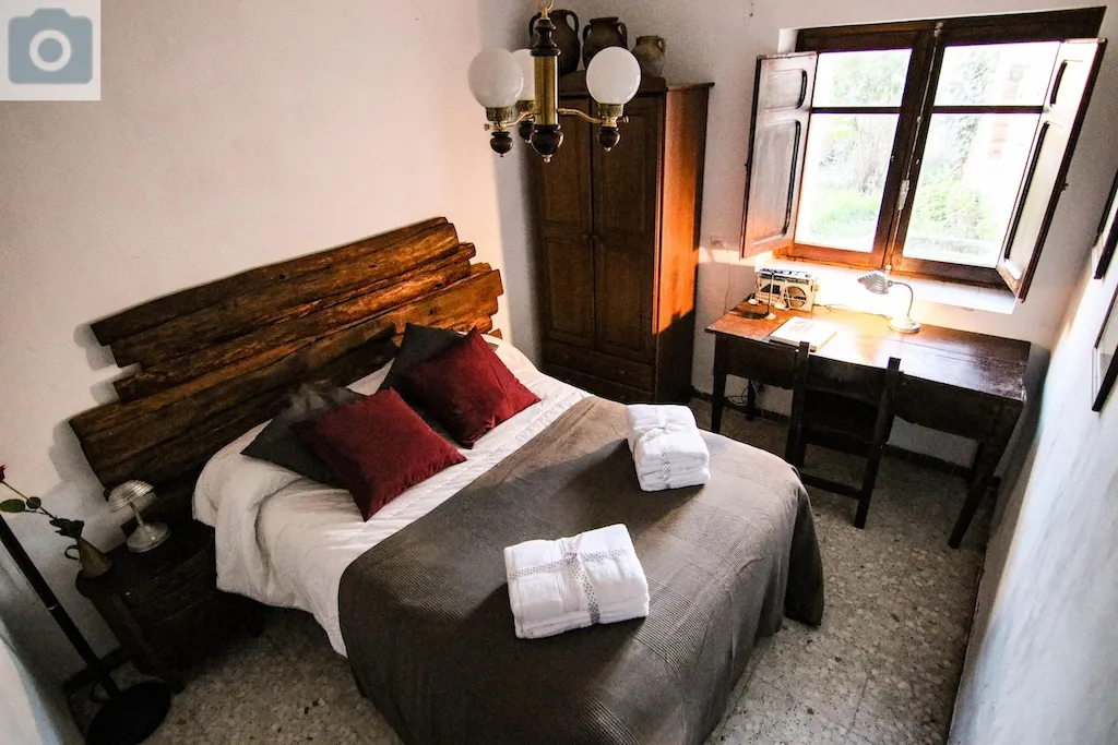 Habitación de matrimonio con armario y sábanas sobre la cama